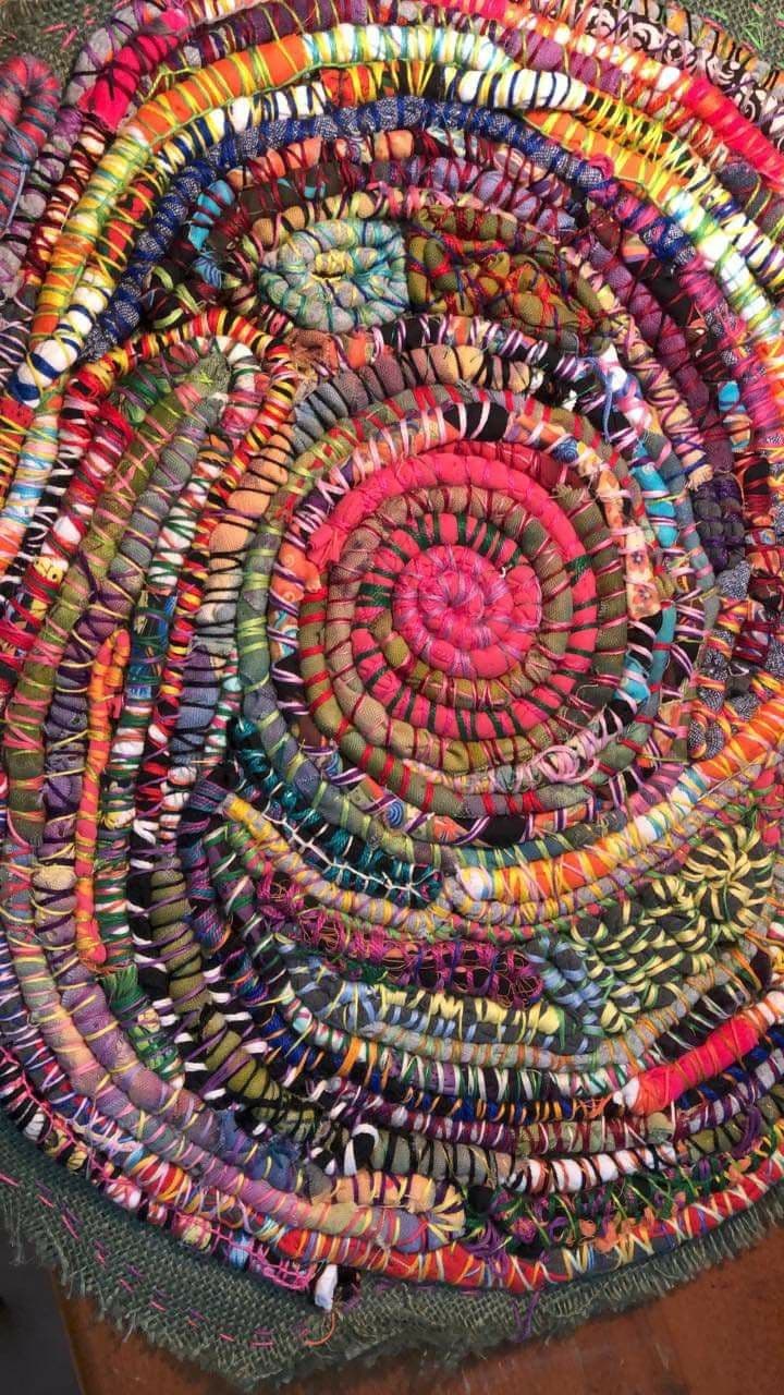 Tapis rond multicolore en spirale, fabriqué à partir de bandes de tissu recyclé cousues et enroulées.