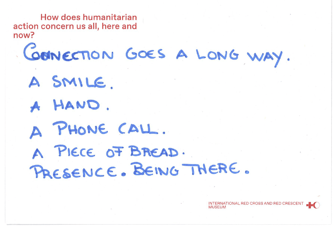 Text in English written on a postcard saying: ‘Connection goes a long way. A smile. A hand. A phone call. A piece of bread. Presence, being there.’