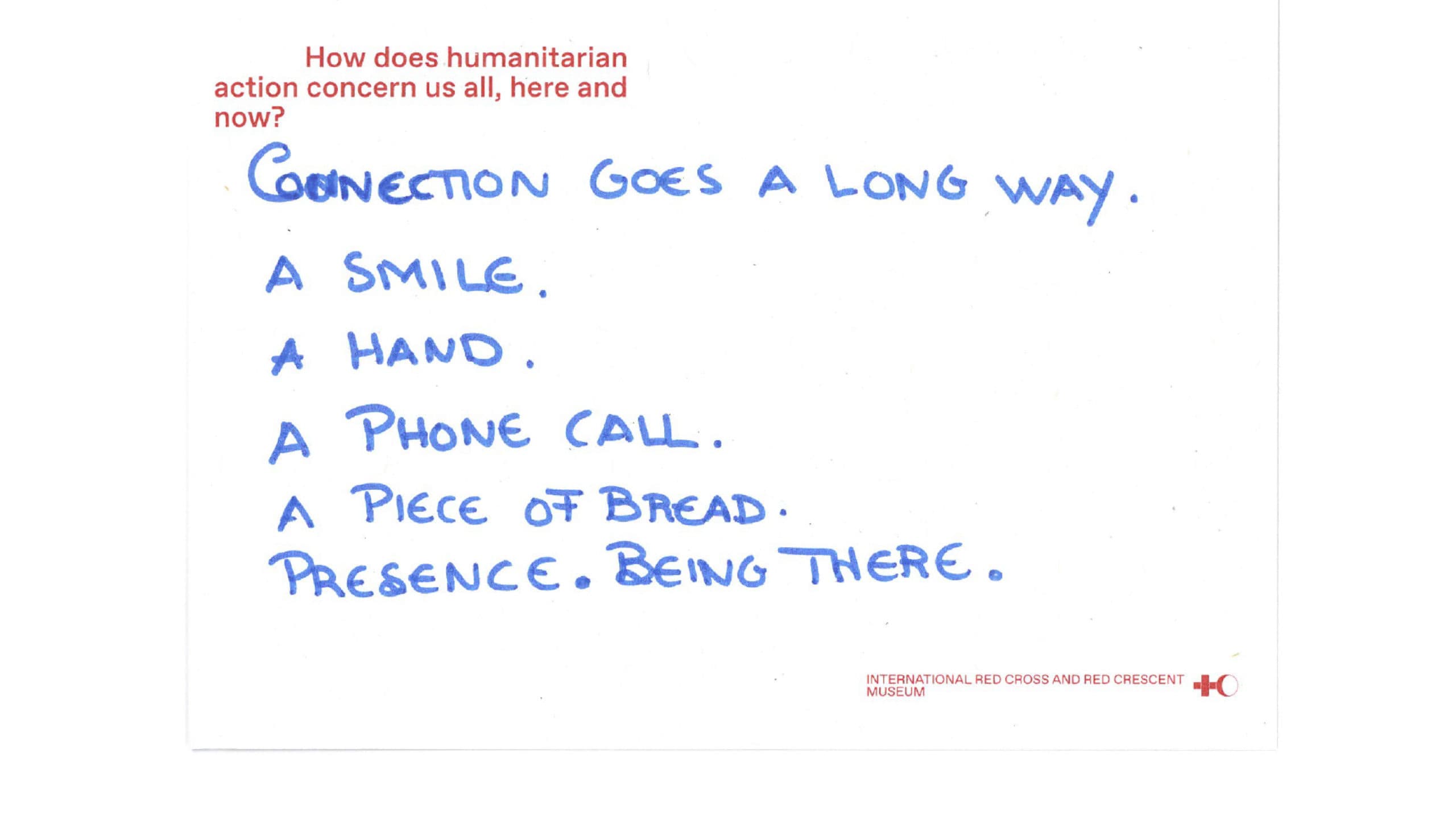 A scan of a postcard on which the question ‘How does humanitarian action concern us all, here and now?’ is written in red, and the answer ‘Connection plays an important role. A smile, a hand, a phone call, a piece of bread, presence. Being there.’ is written in blue.